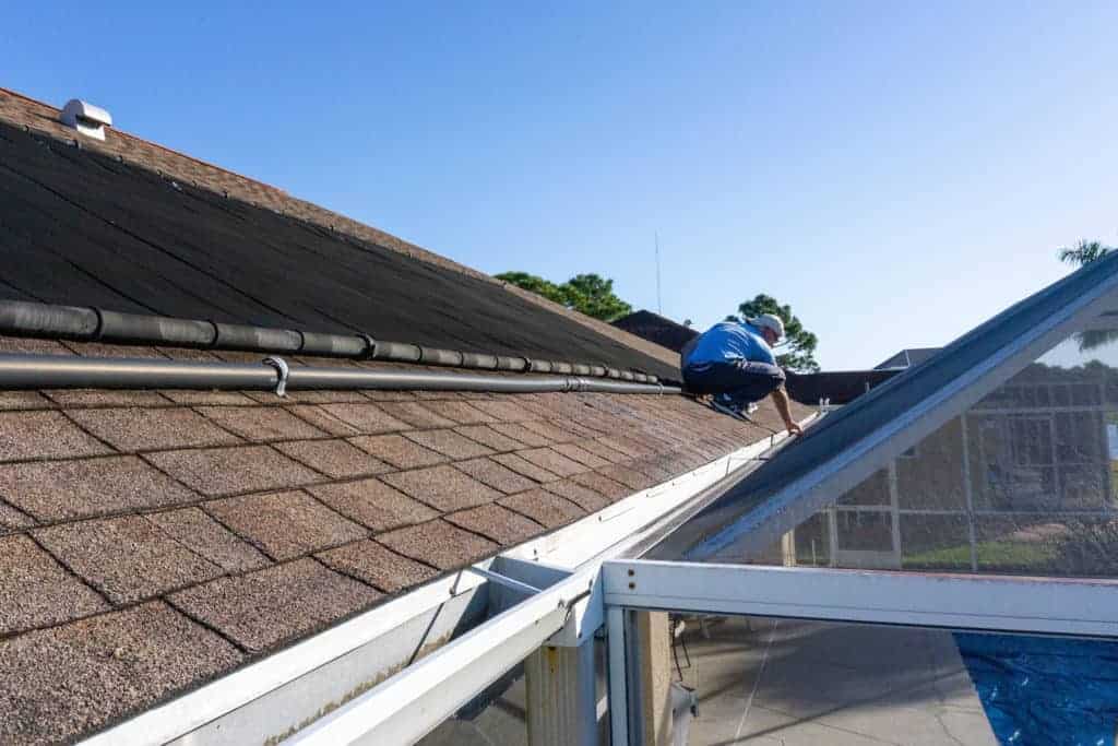 man on roof preforming diy roof repair