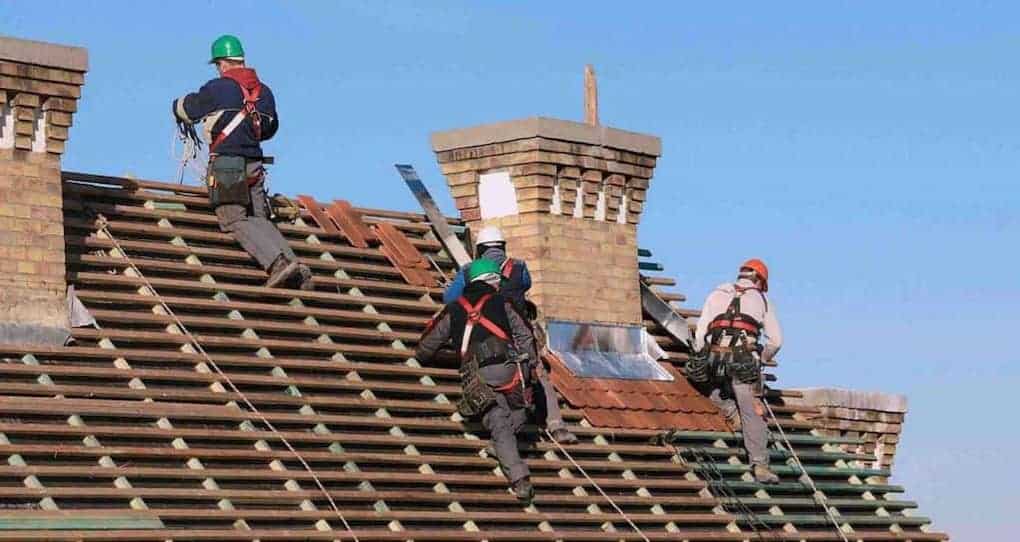 workers on roof installing clay tiles; diy roof replacement