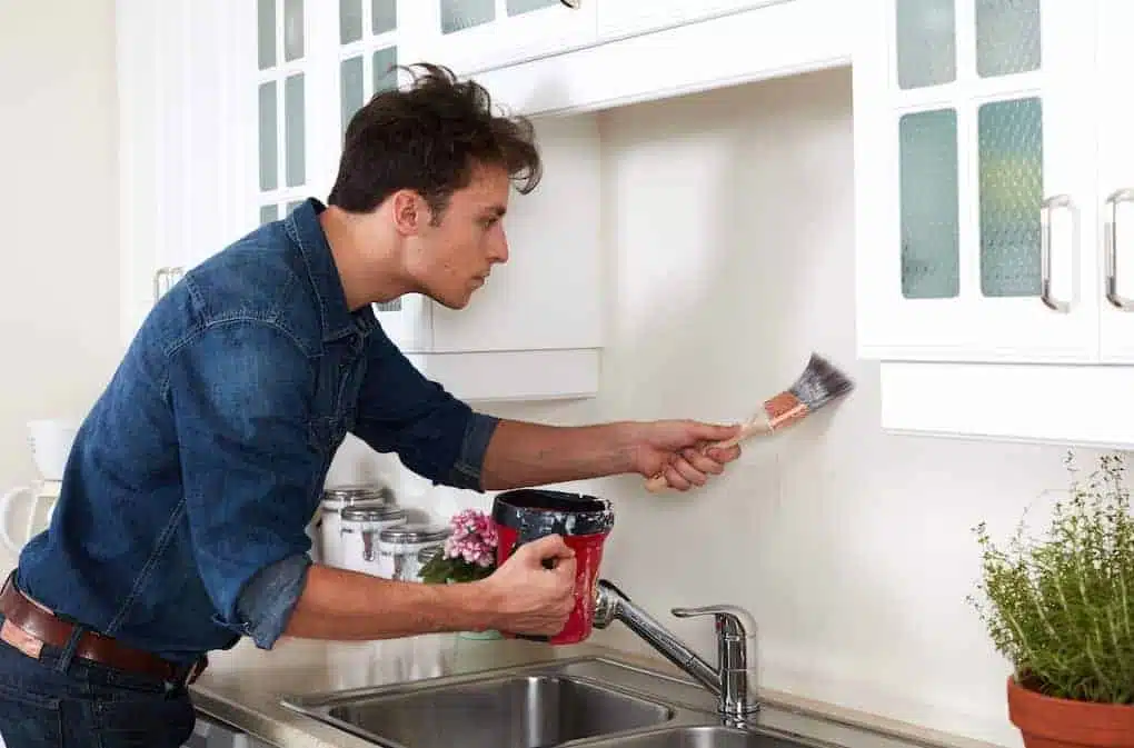 a man painting as one of the kitchen remodeling ideas
