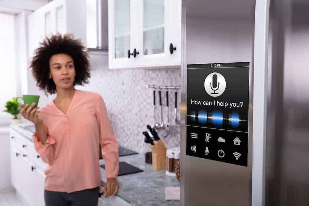 young woman standing next to smart refrigerator in kitchen; kitchen remodeling ideas
