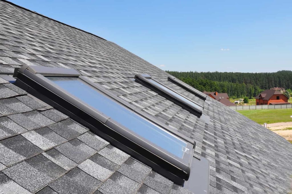 Attic skylight. Asphalt Shingles House Roofing Construction with Attic Roof windows, skylights waterproofing.