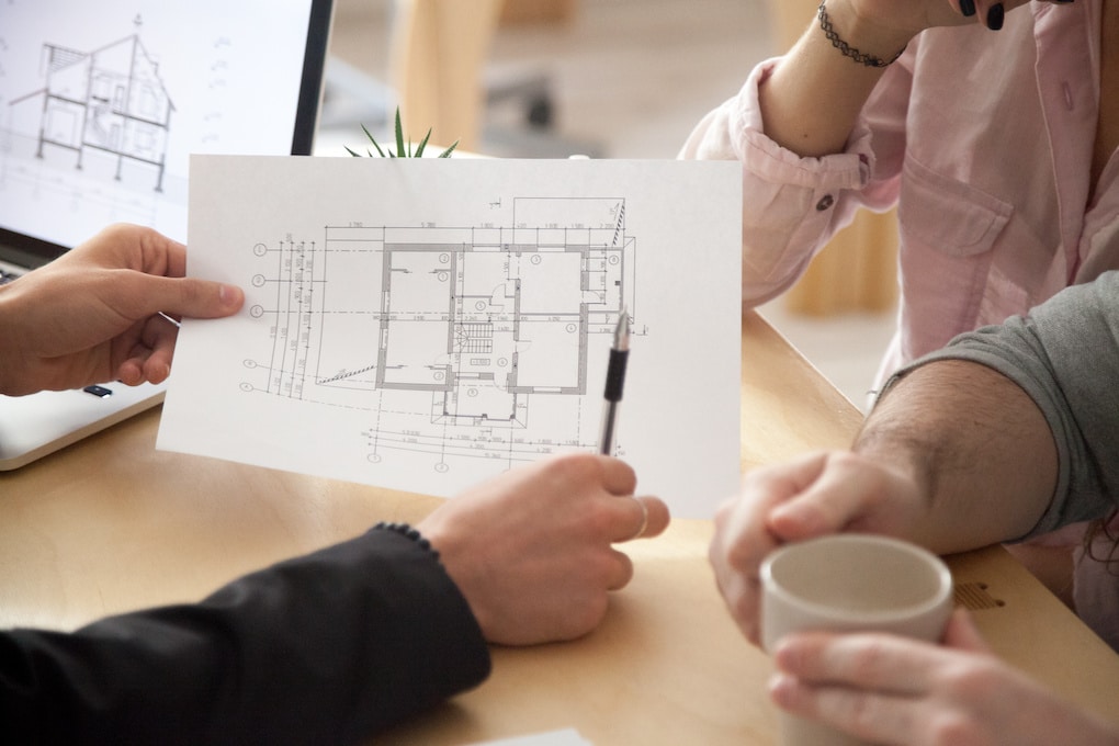 couple looking at interior design plan with contractor; renovate or move