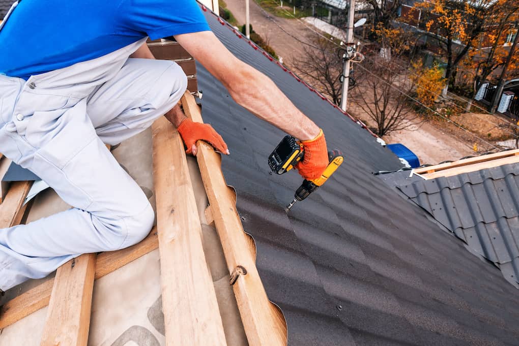 a professional roofer covers repairs during roof replacement in fall