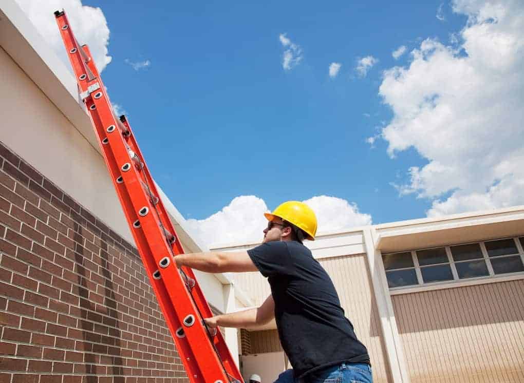 man demonstrating proper roofing safety while climbing ladder