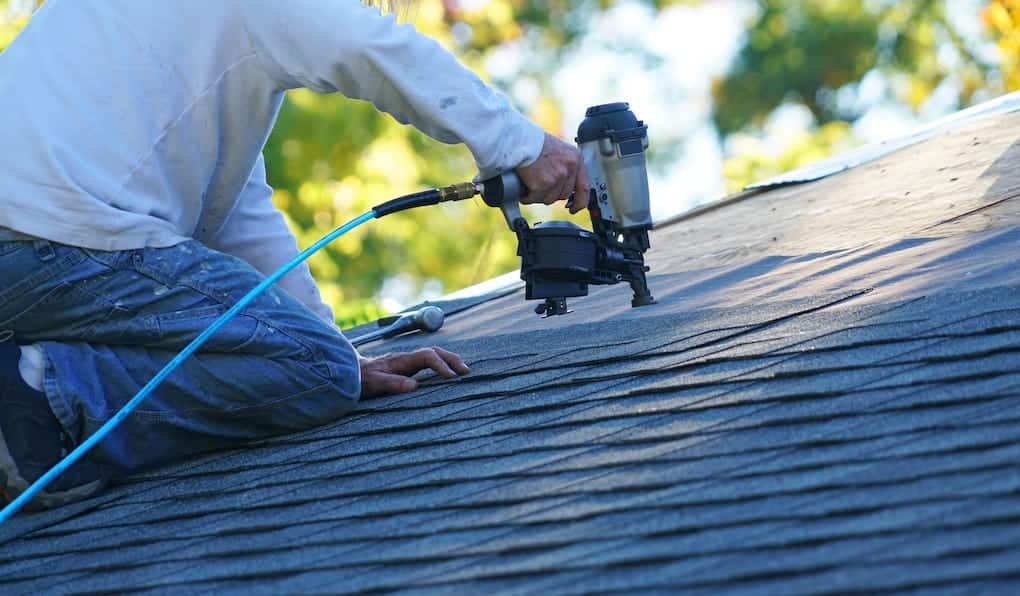 roofing contractors in arlington installing asphalt shingles with nail gun