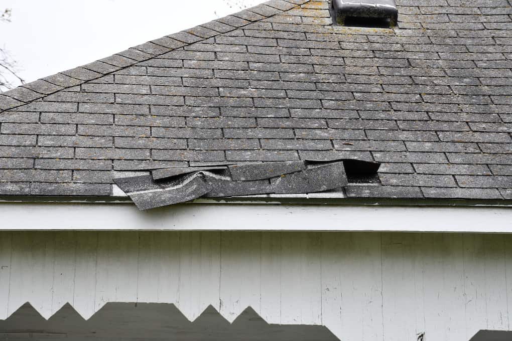 shingle storm damage on roof of white home